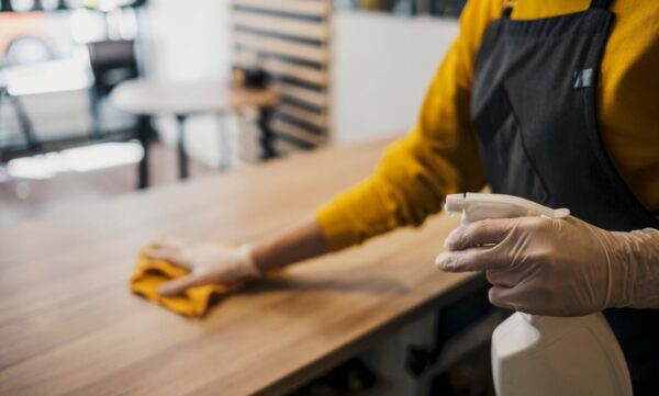 side-view-female-barista-cleaning-table-while-wearing-latex-gloves_23-2148522930